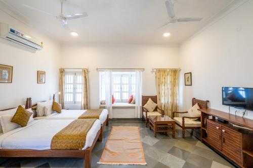 a bedroom with two beds and a flat screen tv at Sajjan Niwas in Udaipur