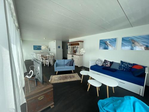 Leben im Hafen am idyllischen Murtensee في Guévaux: غرفة معيشة مع أريكة زرقاء وطاولة