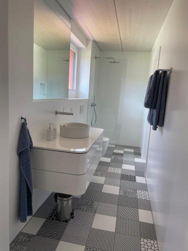 a white bathroom with a sink and a mirror at Leben im Hafen am idyllischen Murtensee in Guévaux
