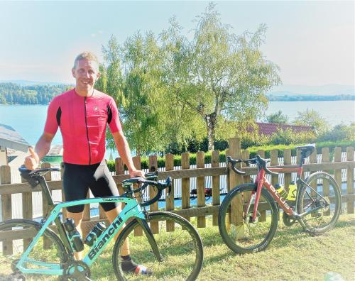 un hombre está de pie junto a dos bicicletas en Apartments Am See en Klopein am Klopeiner See