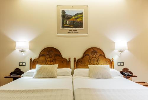 two beds in a bedroom with two lamps on the wall at Don Paco in Llanes