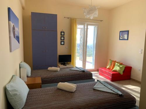 Cette chambre comprend deux lits et un canapé rouge. dans l'établissement ΑΤΕΛΙΟΥ ΣΤΟΥΝΤΙΟ, à Vári