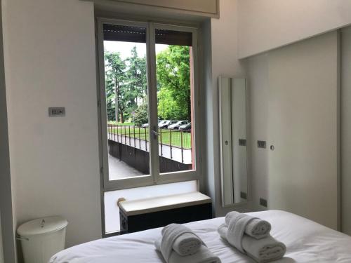una camera con letto e finestra con asciugamani di CaseOspitali - RAFFAELLA moderno bilo vicino al SAN RAFFAELE a Segrate