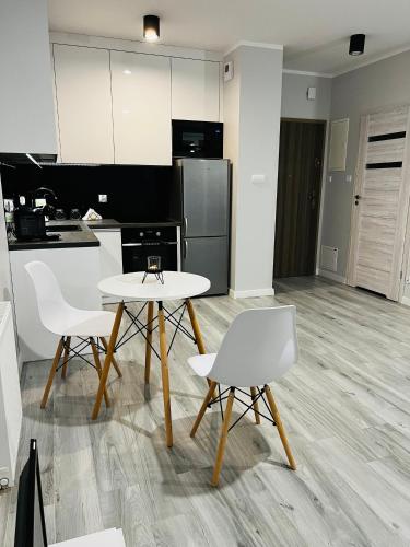 a kitchen with a table and two white chairs at Apartment Comfort in Bartoszyce