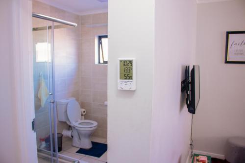 a bathroom with a toilet and a glass shower at Charms and bows studio apartment -near ORT airport in Boksburg