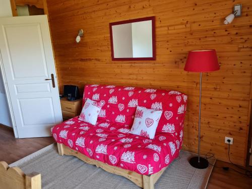 a red couch sitting in a room with a lamp at SCI Les Prunelles in Orelle