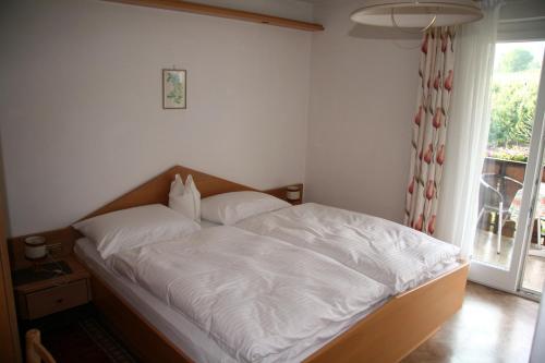 Schlafzimmer mit einem Bett mit weißer Bettwäsche und einem Fenster in der Unterkunft Gaulbachhof in Naturns
