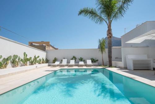 a swimming pool in the backyard of a house with a palm tree at Il Moro Camere&Relax in San Vito lo Capo