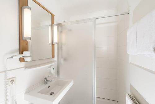 Baño blanco con lavabo y espejo en Good Morning Erfurt, en Erfurt