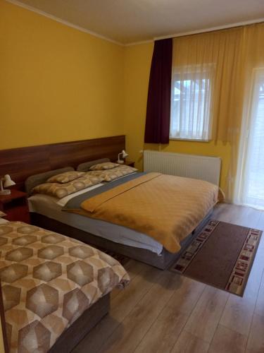 two beds in a bedroom with yellow walls at Boglárka Vendégház in Mosonmagyaróvár