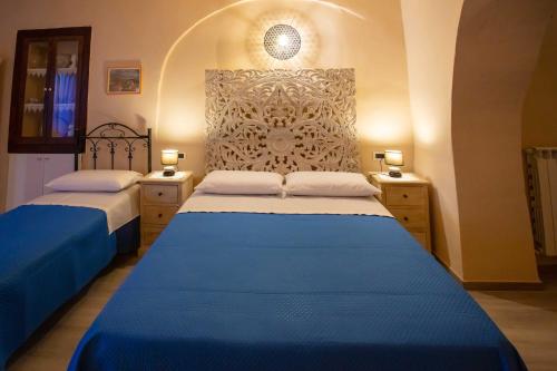 Aliano的住宿－Il Paesaggio Lunare，一间卧室配有两张带蓝色床单和灯具的床。