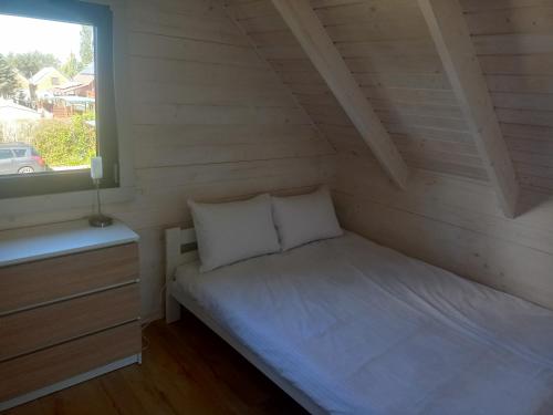 Łóżko w małym pokoju z oknem w obiekcie Manta domki letniskowe w Sianożętach