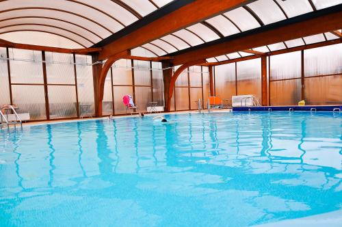 a large indoor swimming pool with blue water at Hotel Maxim in Oradea