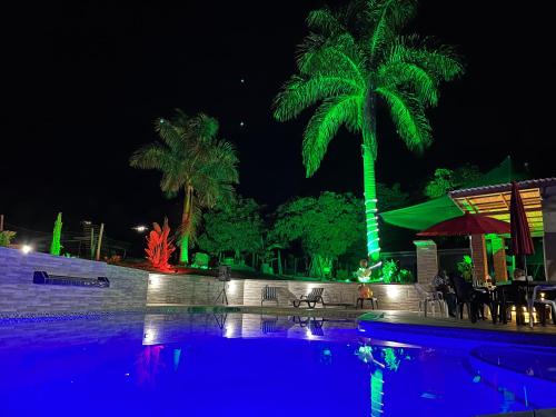 a pool with a palm tree at night at Monteverde Holiday Apartments in Buga