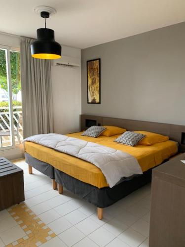 una camera da letto con un grande letto con una coperta gialla di Hibiscus Manganao 1905 a Saint-François