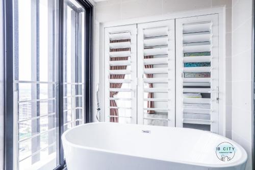 a white bath tub in a room with windows at Mid Valley Southkey Mosaic by Greatday in Johor Bahru