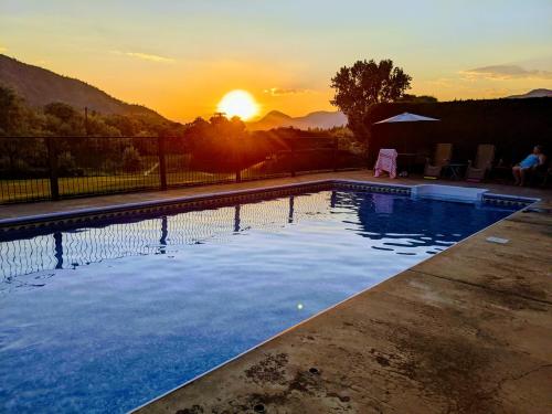 a swimming pool with the sunset in the background at Kamloops Log Home Bed and Breakfast in Kamloops