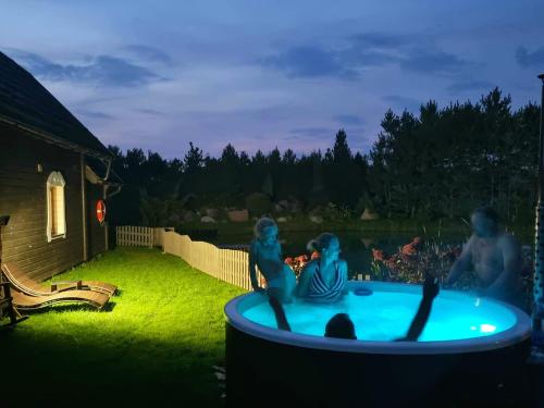 un grupo de personas sentadas en una piscina por la noche en Sodyba Atgaiva, en Lazdininkai