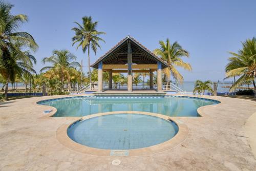 - une piscine avec un kiosque et des palmiers dans l'établissement Cabaña Playa Caimán 1, à Coveñas