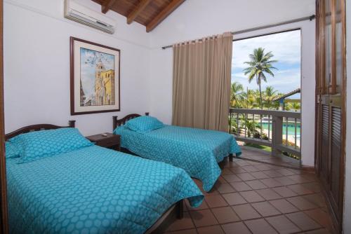 Habitación de hotel con 2 camas y balcón en Cabaña Playa Caimán 1, en Coveñas
