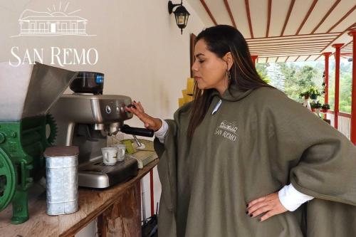 a woman standing in front of a coffee machine at Hotel Rural SAN REMO in Santa Rosa de Cabal
