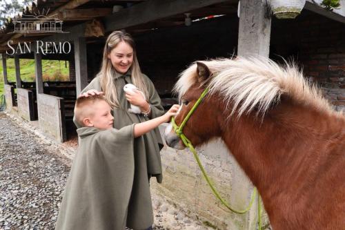 a woman and a young boy petting a horse at Hotel Rural SAN REMO in Santa Rosa de Cabal