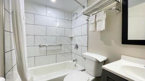 Baño blanco con aseo y lavamanos en Days Inn by Wyndham Columbus IN, en Columbus