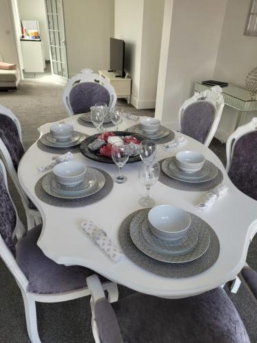 einen weißen Tisch mit Tellern und Weingläsern darauf in der Unterkunft Bracken Dene in Lynemouth