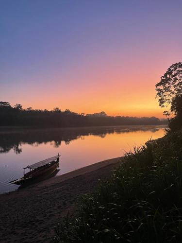 a boat on the shore of a lake at sunset at Tambopata Edosikiana Ecolodge in Tambopata