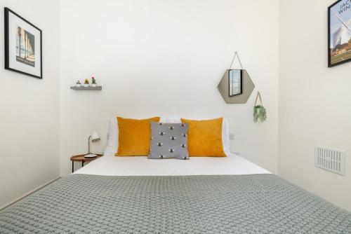 um quarto branco com uma cama com almofadas cor-de-laranja e cinzenta em Beautiful, central, 3 min walk from beach, 2 King doubles em Brighton & Hove