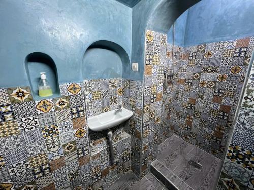 a bathroom with a sink and mosaic tiles on the wall at Riad Verus in Fès