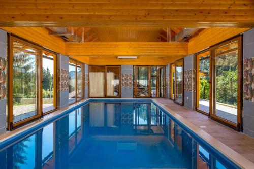 a swimming pool in a house with windows at Greenhouse Ella with heated pool in Tršće