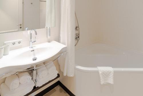 a white bathroom with a sink and a tub at Hotel Spiess & Spiess in Vienna