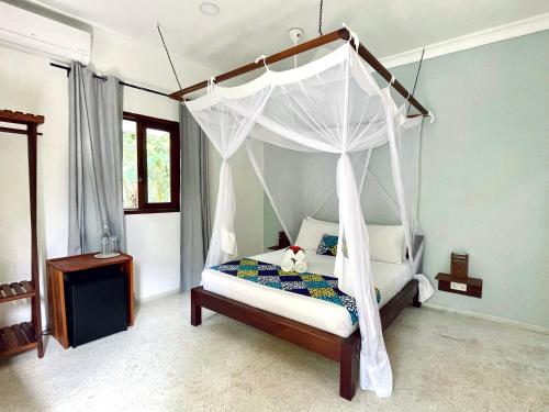 a bedroom with a canopy bed with a teddy bear on it at Gaia Villas in Nungwi