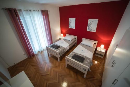 a room with two beds and a red wall at Villa Magdalena, Biograd na Moru in Biograd na Moru