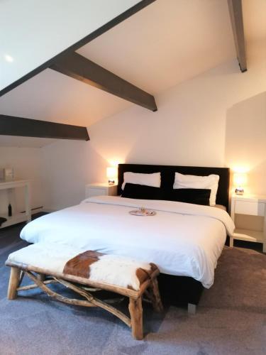 a bedroom with a large white bed and a bench at B&B/Boertel de Meander in Oirschot