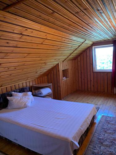 ein Schlafzimmer mit einem großen Bett in einem Holzzimmer in der Unterkunft Casa Lorena in Sărata-Monteoru