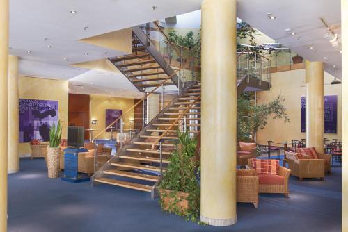 a spiral staircase in a lobby with chairs and plants at Radisson Blu Fürst Leopold Hotel in Dessau