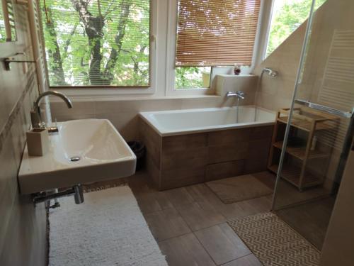 a bathroom with a tub and a sink and a window at Attic Apartment in Piešťany