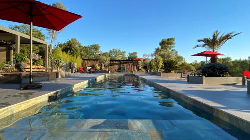 einen Pool in einem Resort mit einem roten Regenschirm in der Unterkunft LES ROCHES DE BAUDISSET in Saint-Paul-en-Forêt