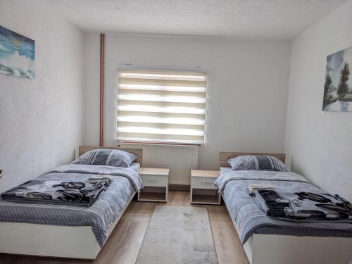 two beds in a room with a window at Apartmani Drinska in Foča