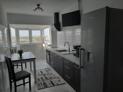 a kitchen with a sink and a table and a refrigerator at Apartament DeltaView Deluxe Sulina in Sulina