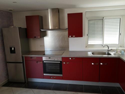 a kitchen with red cabinets and a sink and a refrigerator at Domaine de la Borde in Damparis