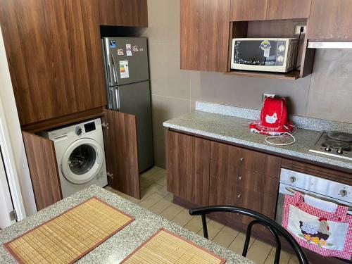 a small kitchen with a refrigerator and a washing machine at departamento Amoblado Paola 1 in Calama