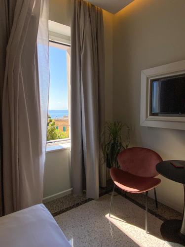 a bedroom with a window and a chair and a table at NoOne Tropea Guesthouse in Tropea