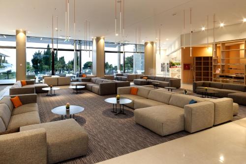 a lobby with couches and tables and windows at Hotel Materada Plava Laguna in Poreč
