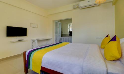 a bedroom with a bed with yellow pillows and a tv at Itsy Hotels Ushodaya Royal Residency in Trivandrum