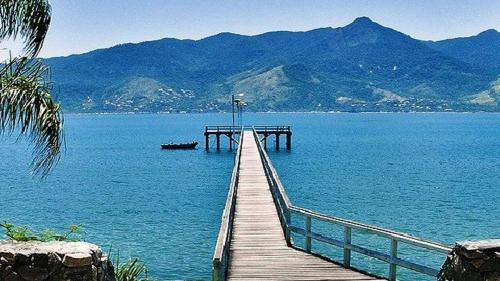 a dock in the middle of a lake with mountains at Casa da Fê in São Sebastião
