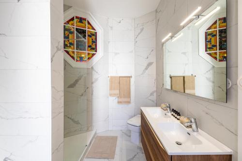 une salle de bain blanche avec un lavabo et un miroir dans l'établissement LUXUEUX APPARTEMENT CENTRE VILLE, à Strasbourg
