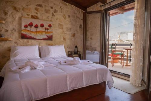 a bedroom with a large white bed with towels on it at Dioni Stone House in Petrokefalo